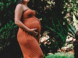 A pregnant student resting her hands on her bump