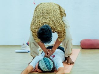 A teacher adjusting a student on the mat
